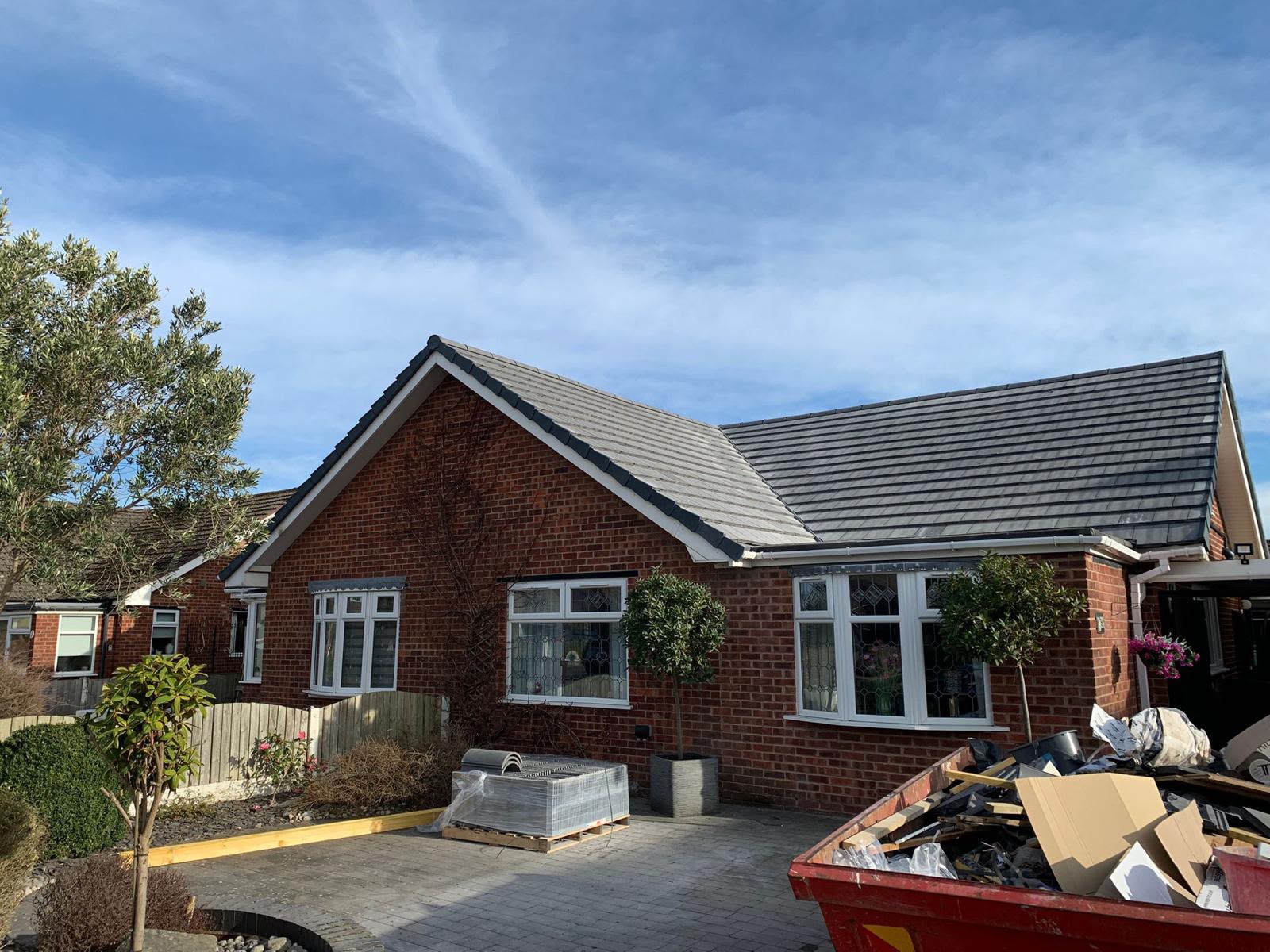 Red brick bungalow with grey tiled roof during exterior works